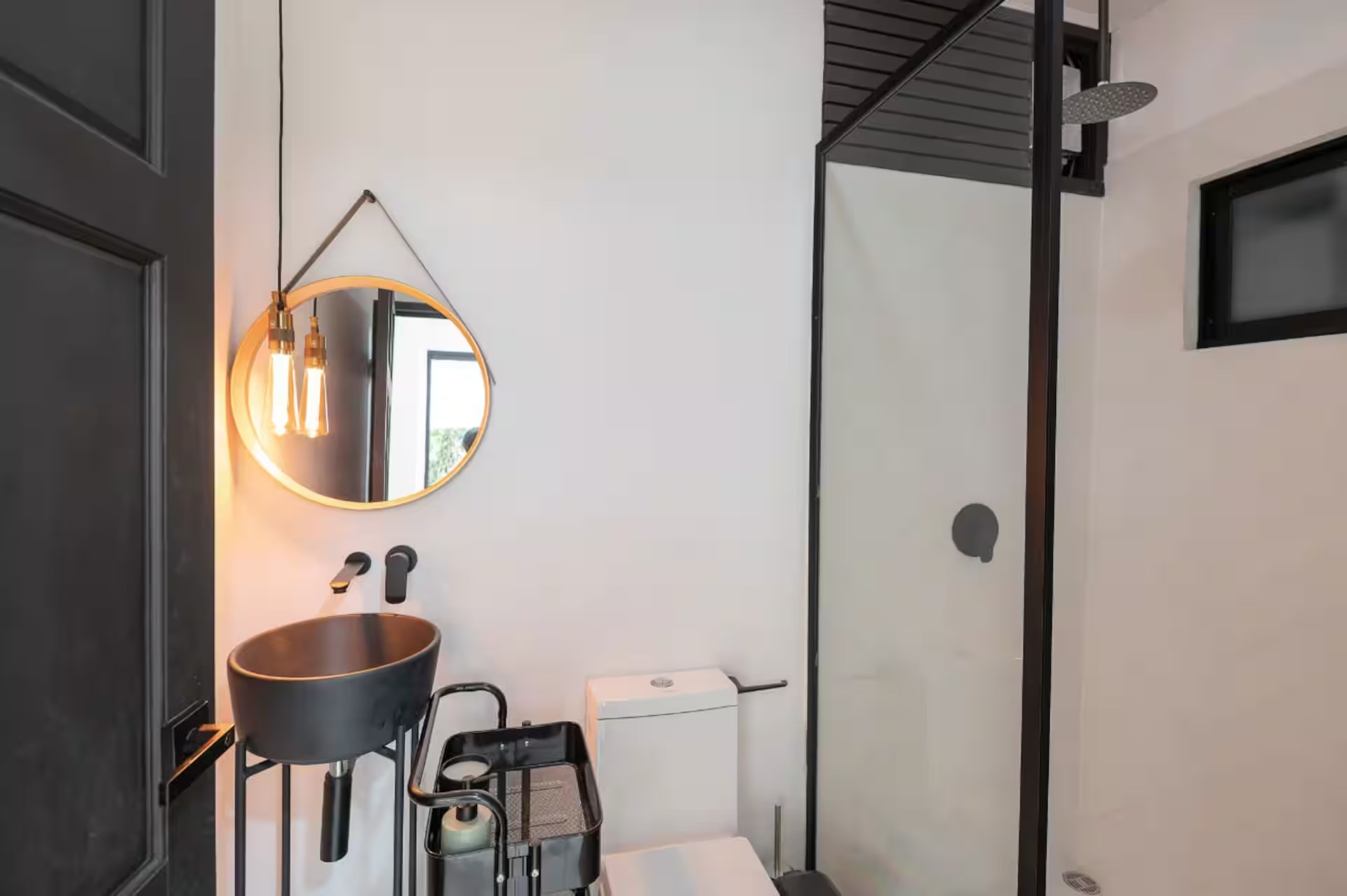 Bathroom with matte black vessel sink, round mirror and glass shower