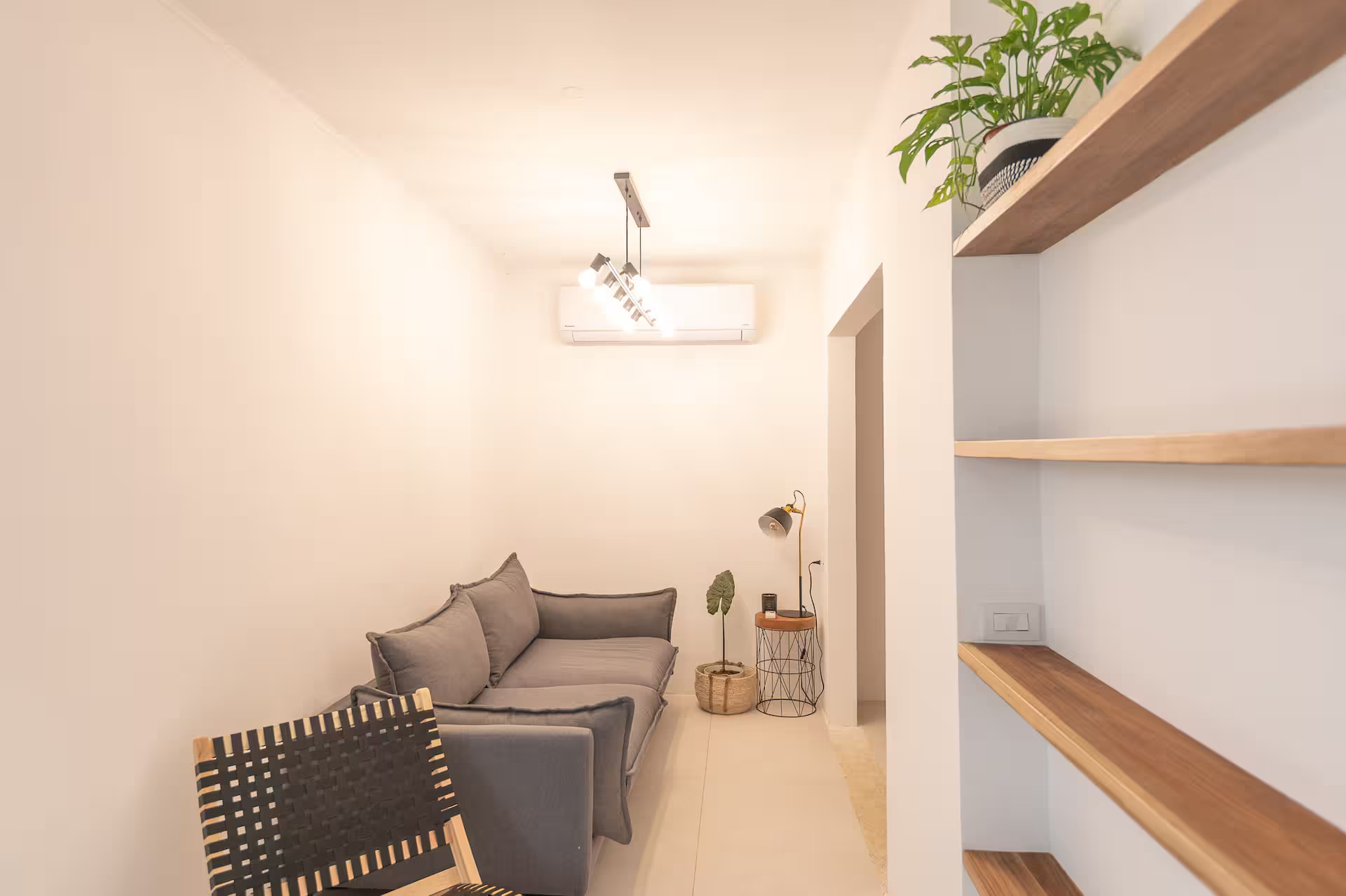 Living room with sofa, woven chair and warm track lighting
